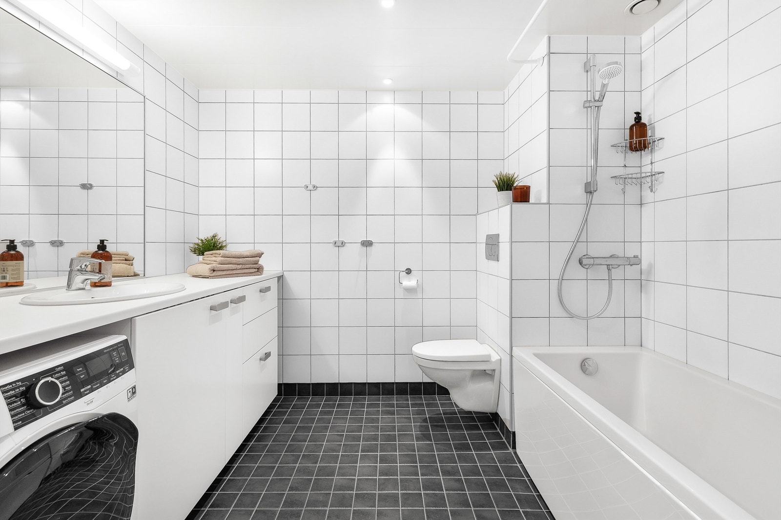 Badet med inngang fra gangen har flislagt gulv med gulvvarme og flislagte vegger. Nedsenket himling med downlights. Galleribilde