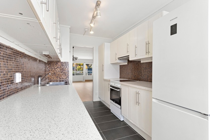 Kjøkkenet har fliser mellom benken og skapene, og belysning under skapene Galleribilde