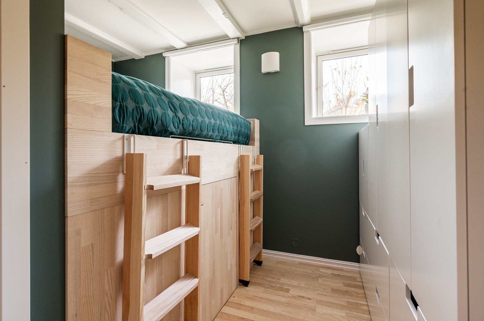 Koselig soverom med grønnmalte vegger og plassbygd seng som har praktisk oppbevaringsplass under. Galleribilde