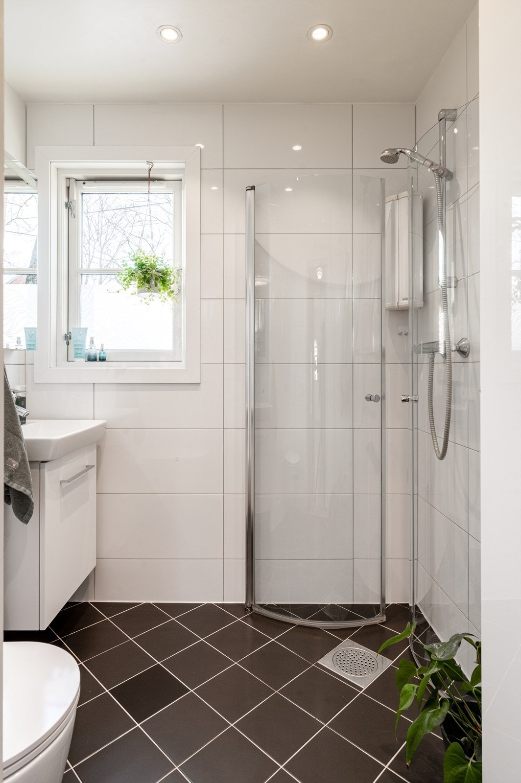 Flislagt bad med dusjnisje, innfellbare dusjdører, vegghengt toalett og servant med ett-greps blandebatteri. Galleribilde