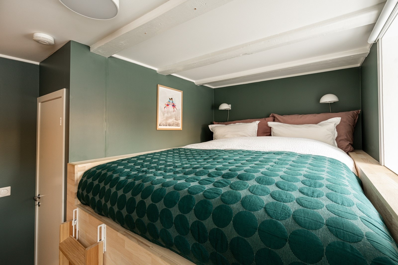 Totalbredden på den plassbygde sengen er ca. 190 cm. På venstre sidebord innerst ved vegg er det uttak for strøm ( ladestasjon med kobling for USB, USB-C og vanlig stikk som kan trykkes opp og ned). Galleribilde