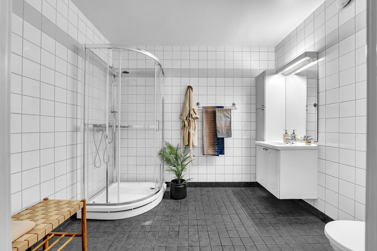 Fint og lyst baderom med servant, dusjkabinett og frittstående toalett. Galleribilde