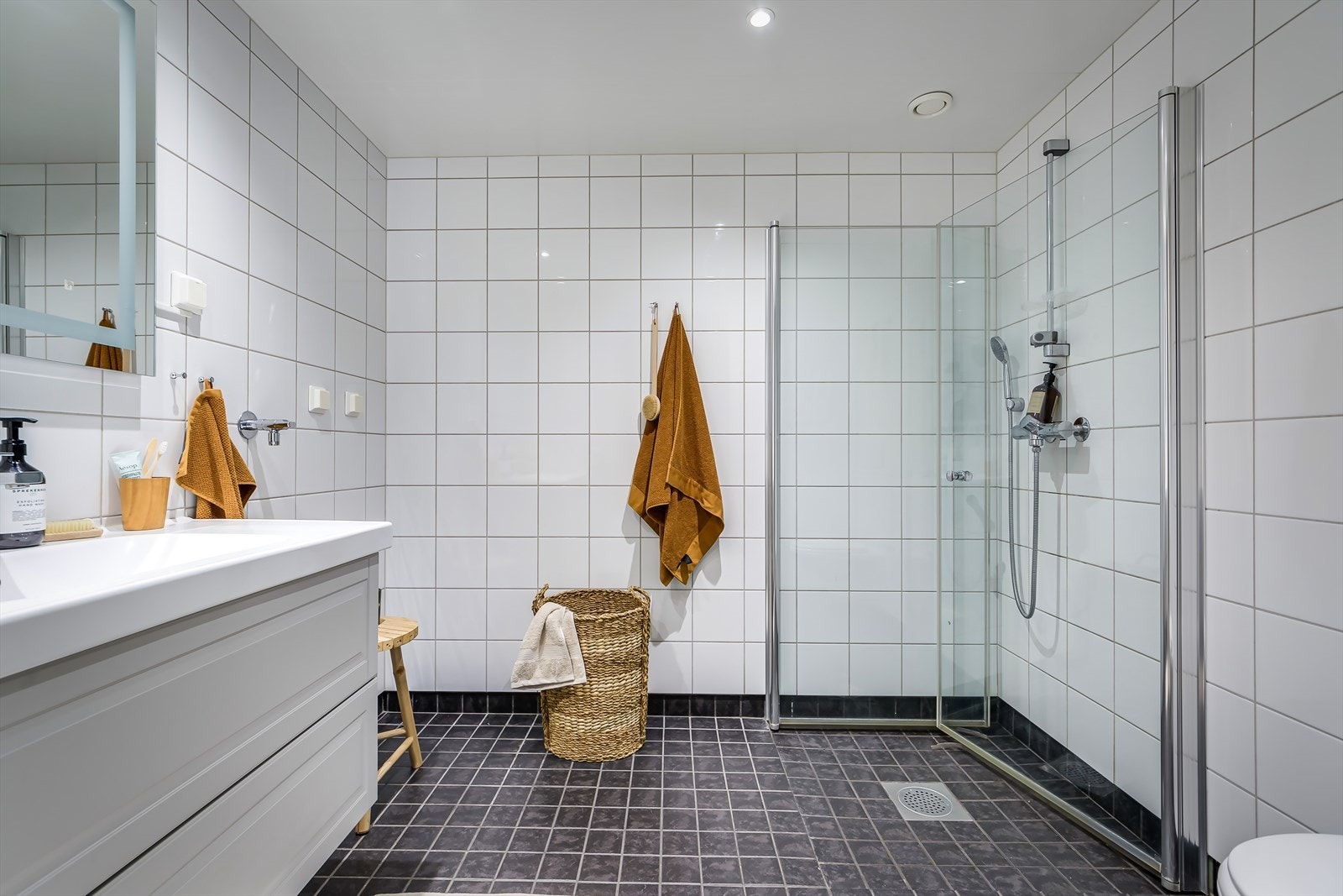 Tidløst og stort bad med flislagte overflater og behagelig gulvvarme. Opplegg for vaskemaskin og tørketrommel, og badet har mekanisk avtrekk Galleribilde