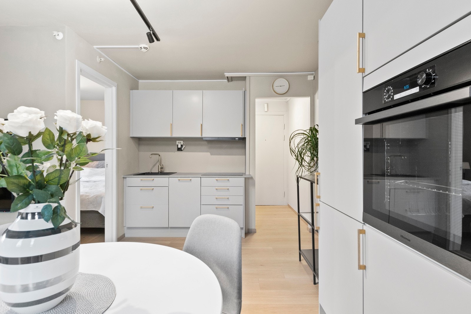 Innredningen har lysegrå, glatte fronter, gullfargede håndtak og lysegrå benkeplate med nedfelt, sort kum. Galleribilde