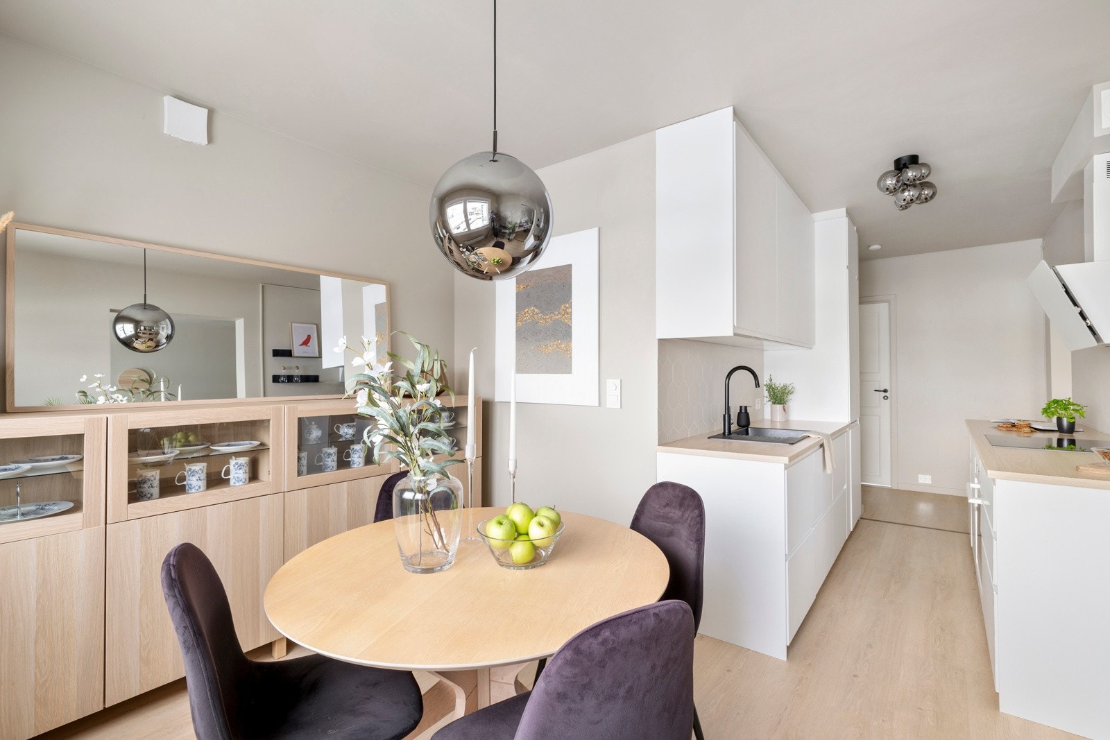 Ikea-innredningen fra 2021/22 er oppført langs to vegger, med hvite, glatte fronter, skuff-i-skuff løsning og oppvaskkum nedfelt i en lys benkeplate av laminat Galleribilde