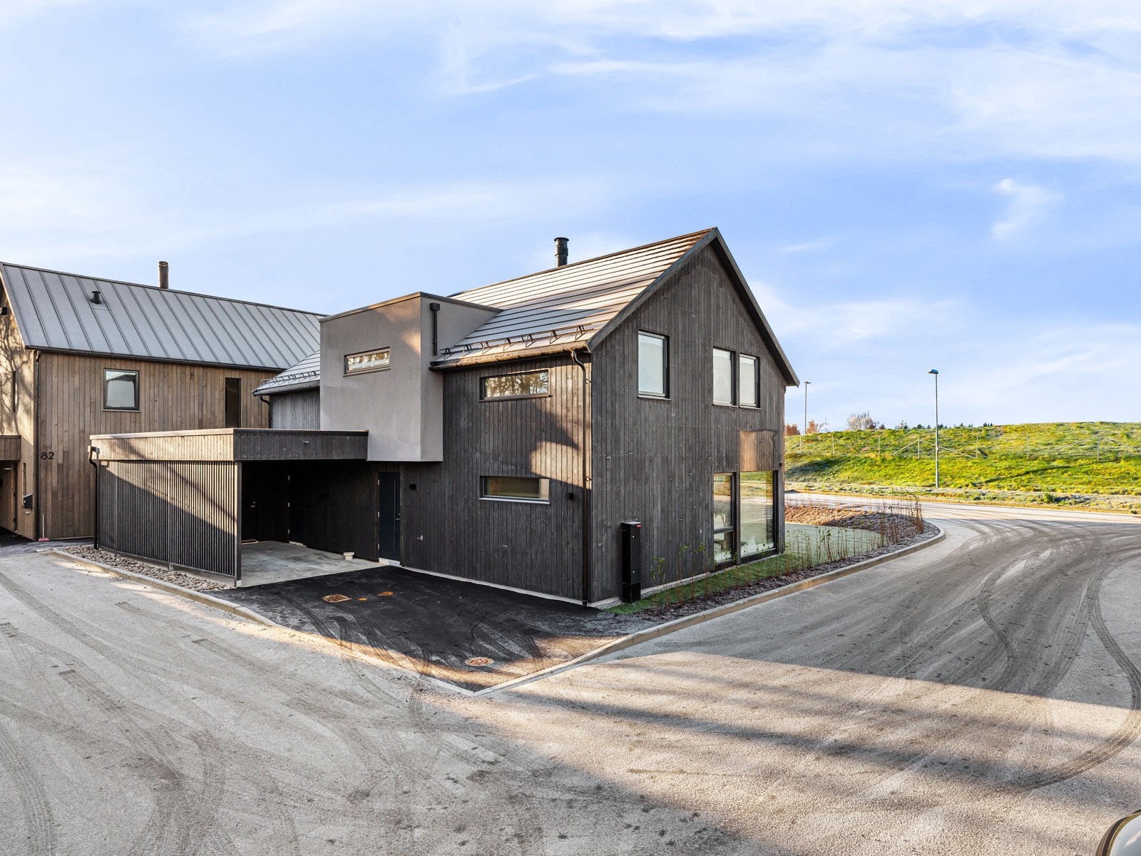 Eiendommen har et pent opparbeidet uteområde med asfaltert gårdsrom, carport og hage Galleribilde