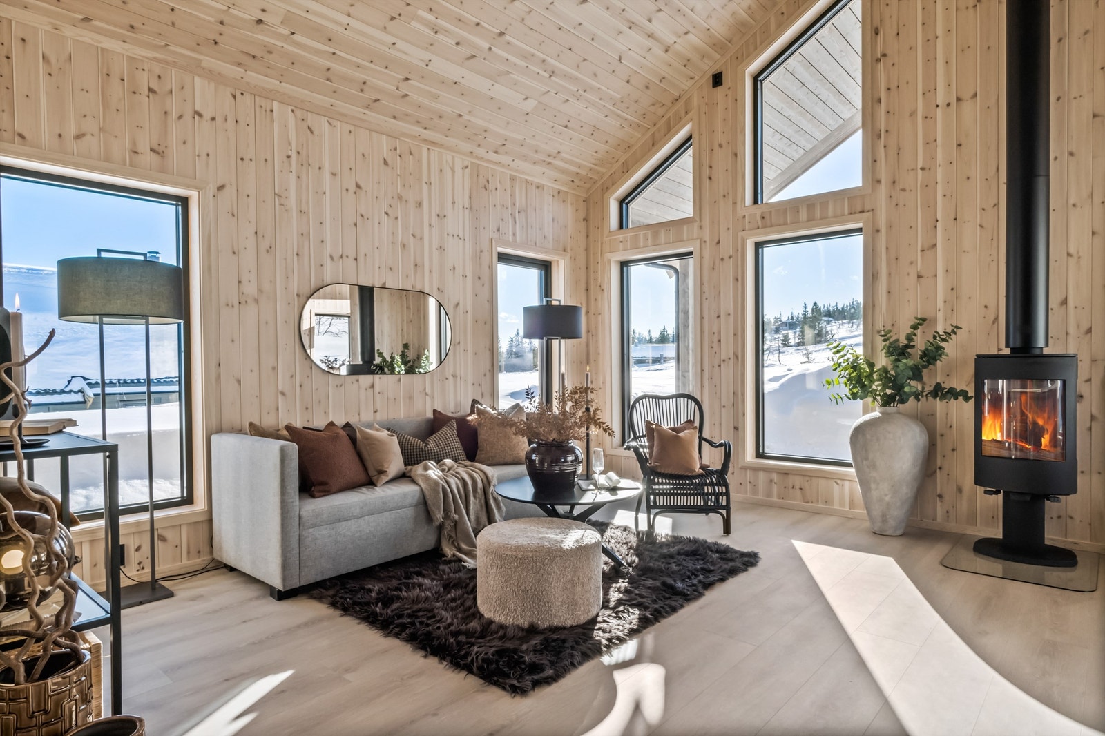 Som et skille mellom kjøkken- og stuesonen er peisen plassert i midten. Dette er en moderne vedovn av type Dovre med gnistsikring foran ildstedet av glassplate Galleribilde