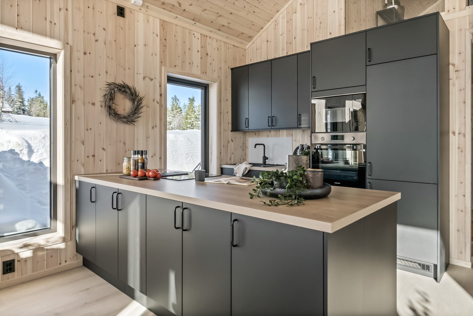 Det er valgt en praktisk og sosial kjøkkenløsning med innredning langs en vegg og kjøkkenøy. Kjøkkenøya har innredning på begge sider Galleribilde