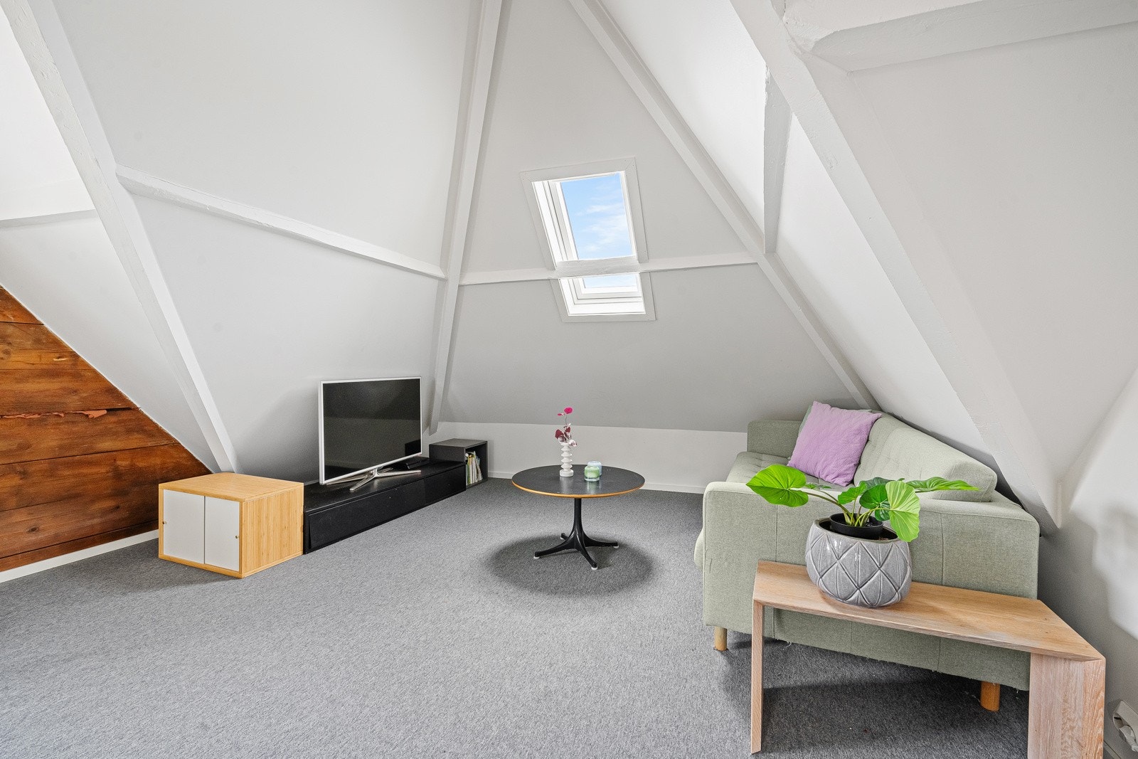 En lys og innbydende loftstue med skråtak og sjarmerende detaljer som skaper en koselig atmosfære. Perfekt som et ekstra oppholdsrom eller arbeidsområde. Galleribilde