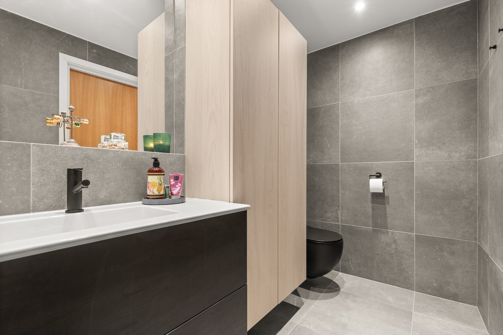 Badet er innredet med vegghengt servantskap og heldekkende servant medinnfelt speil over servant, vegghengt toalett, vegghengt oppbevaringsskap, frittstående badekar med dusjvegg og regndusj. Galleribilde