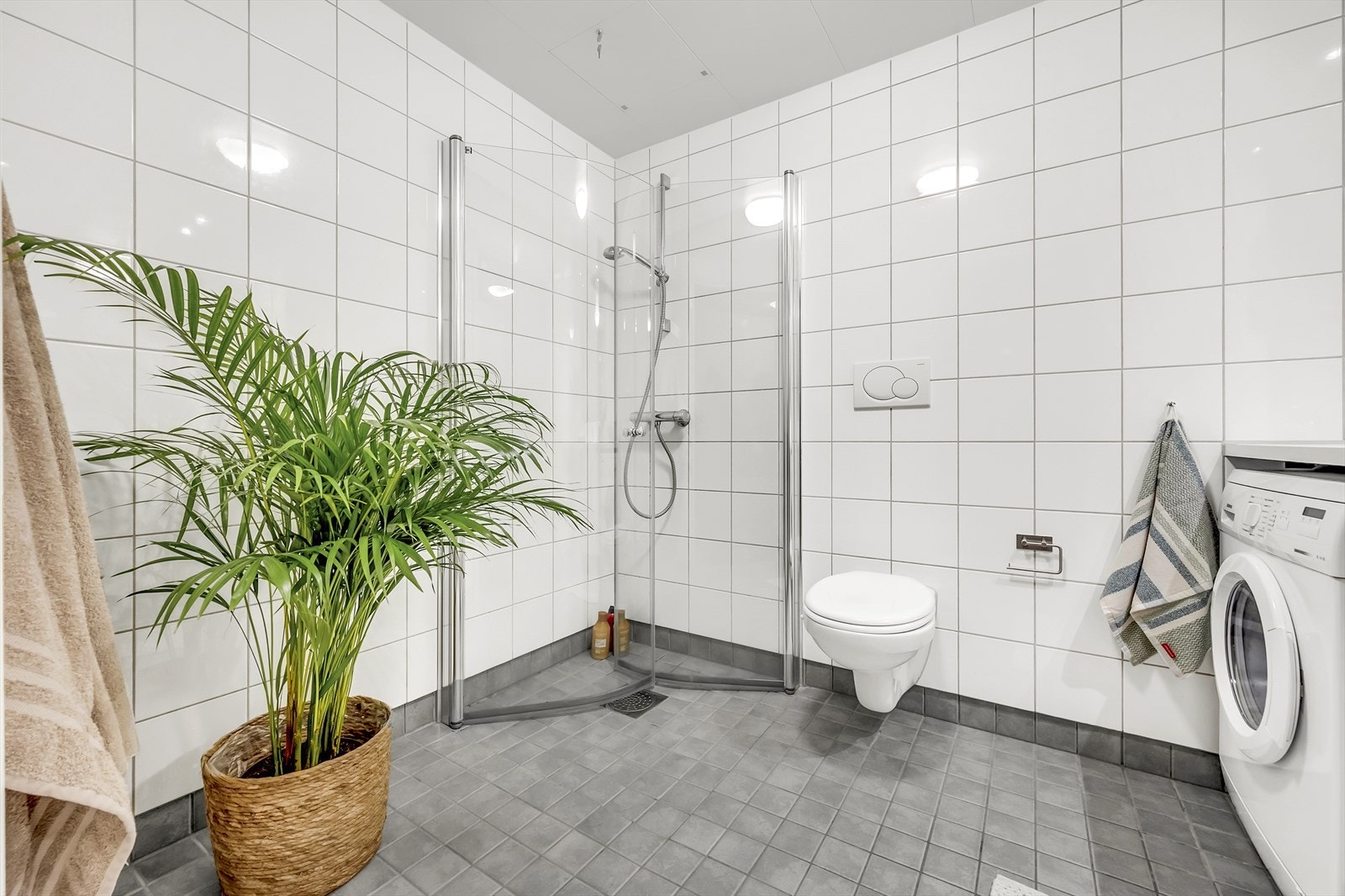 Badet er innredet med vegghengt klosett, servant nedfelt i innredningen og dusjhjørne med svingbare glassdører. Det er også opplegg for vaskemaskin, samt mekanisk avtrekk. Galleribilde