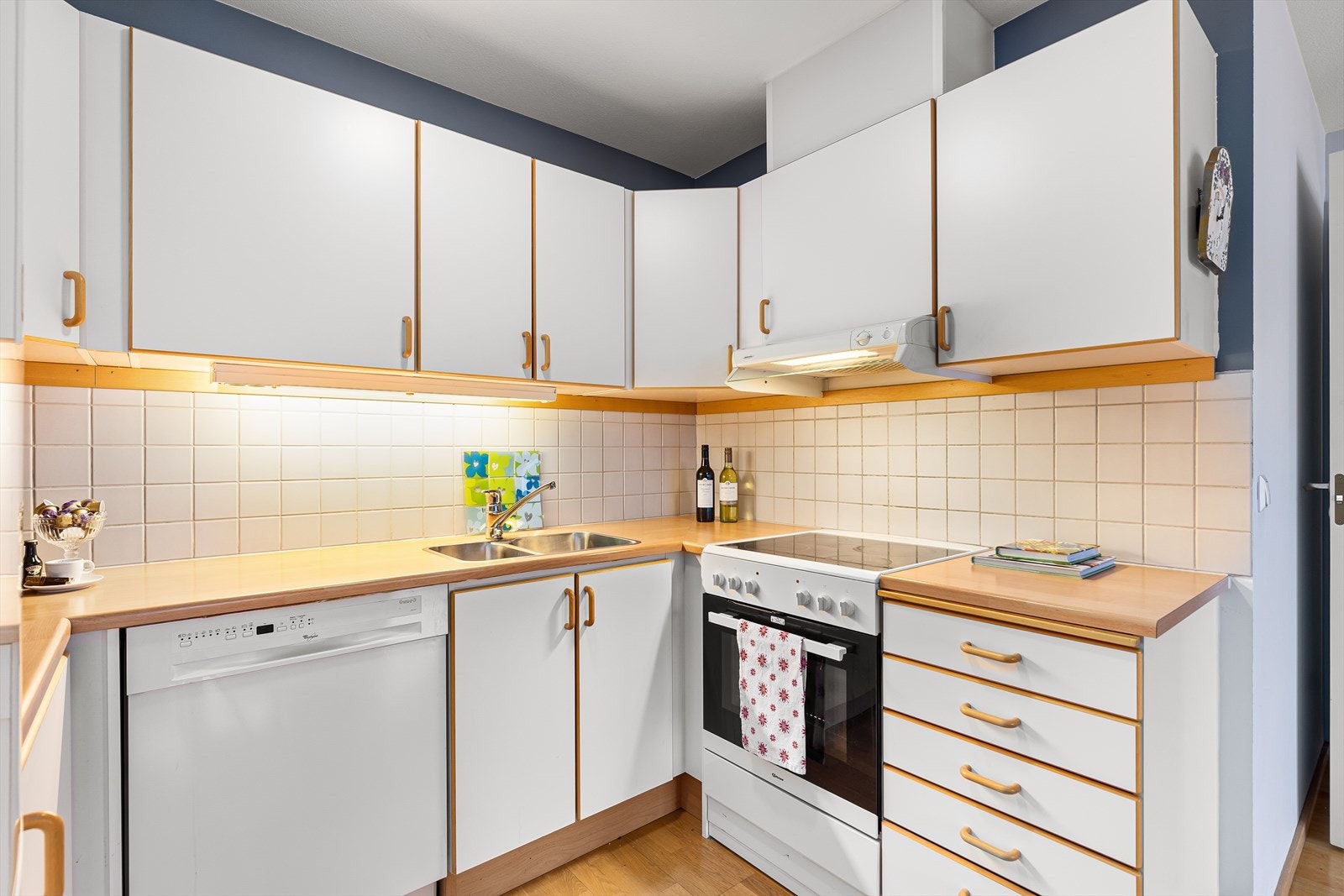 Kjøkkeninnredning har hvite fronter med bøkekantslister. Det er mekanisk avtrekk over komfyr. Galleribilde