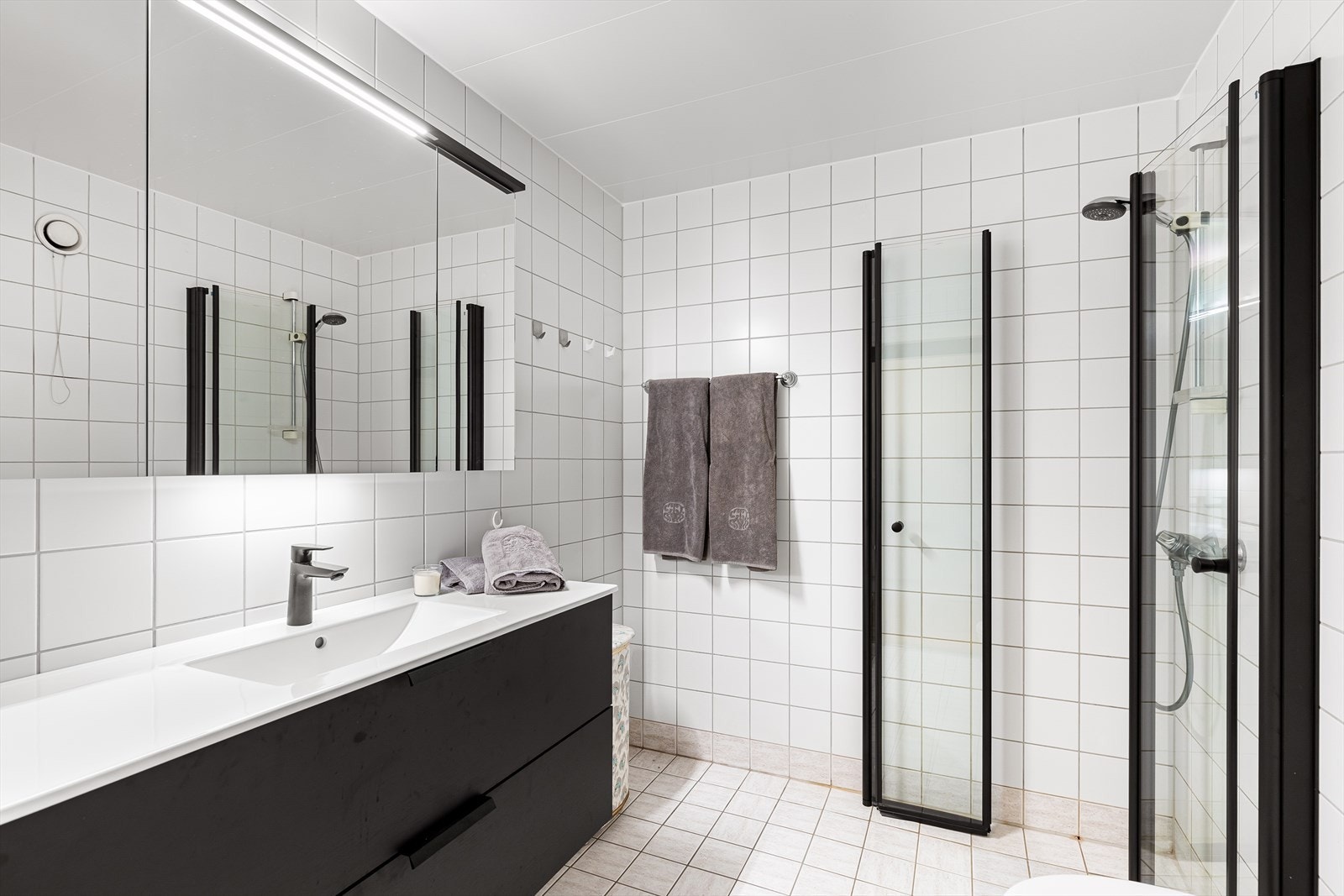 Heldekkende porselensservant med ettgreps servantbatteri og servantskap (2023). 3 speilskap med overliggende lyslist over servant (2023) og nye svingbare dusjdører i herdet glass (2024). Galleribilde