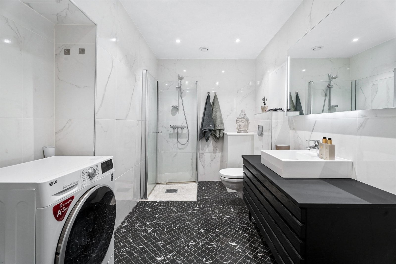 Videre er det dusjhjørne med dører og vegghengt dusjarmatur. Galleribilde