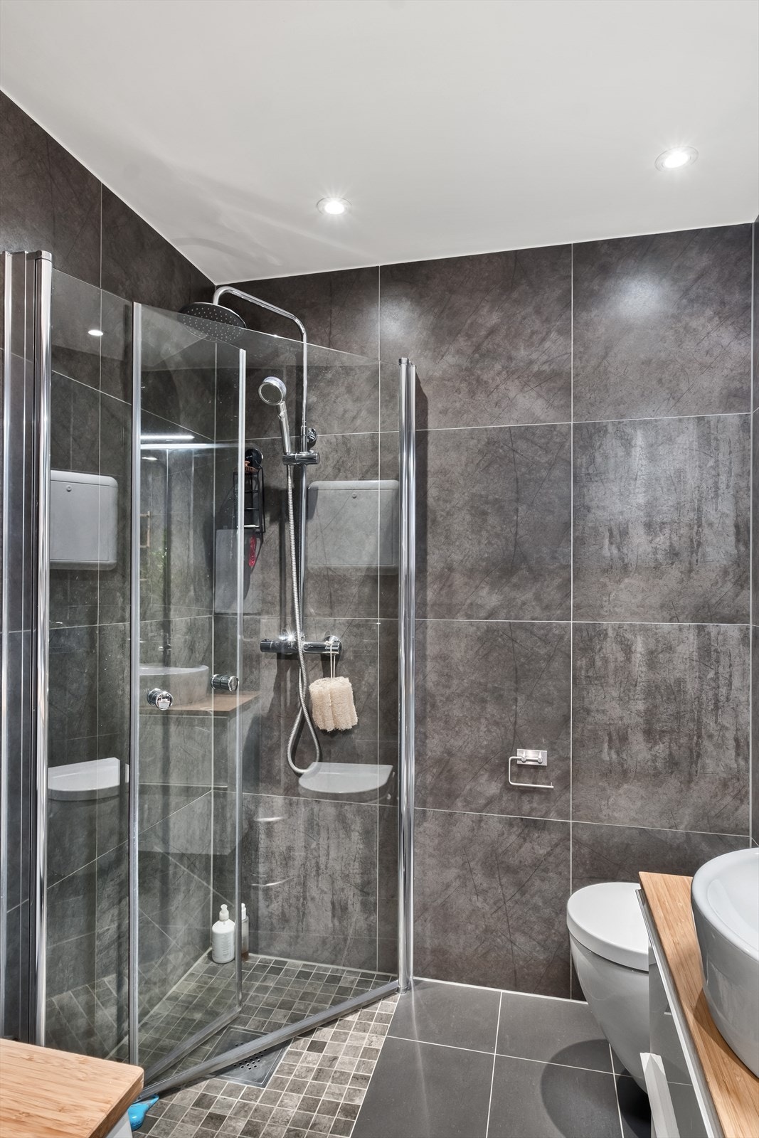 Badet er innredet med vegghengt klosett og dusjhjørne med svingbare glassdører Galleribilde