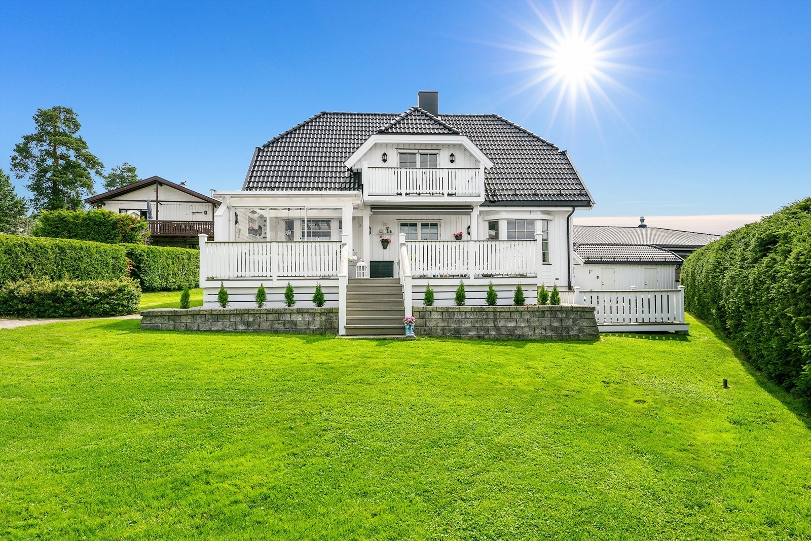 På fremsiden av huset som vender mot vest, er det en stor terrasse som leder ned til hagen. Galleribilde