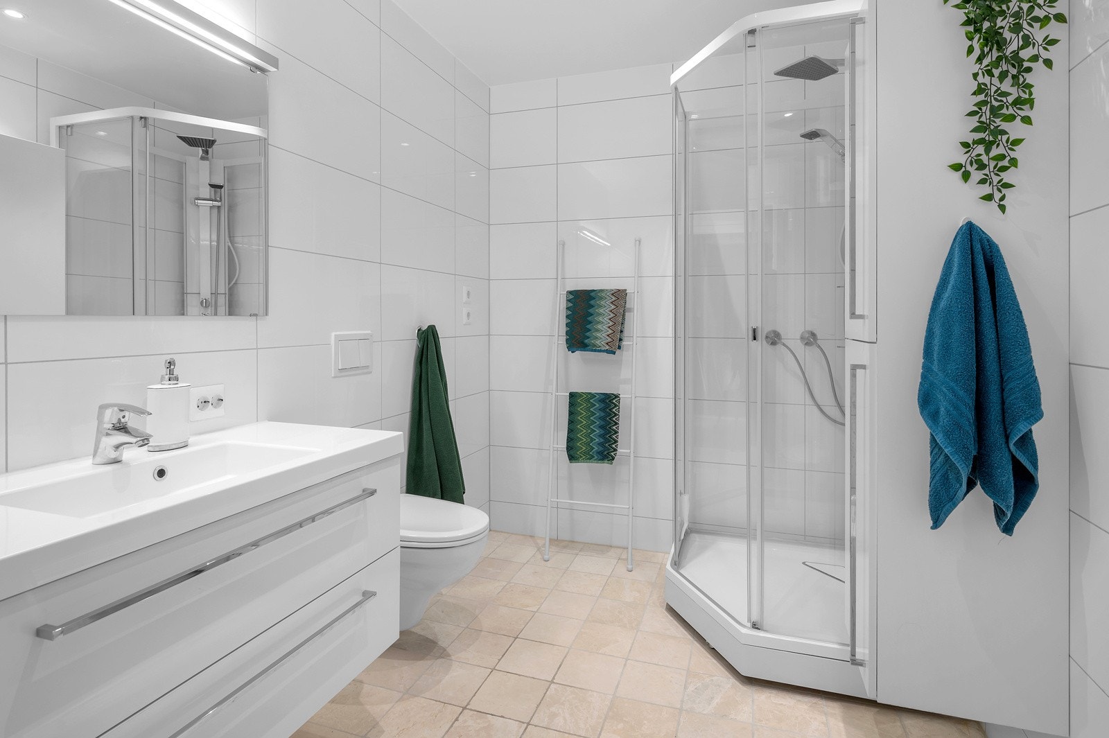 Meget flott flislagt bad med vegghengt toalett, dusjkabinett og servant med skuffer og speil. Galleribilde