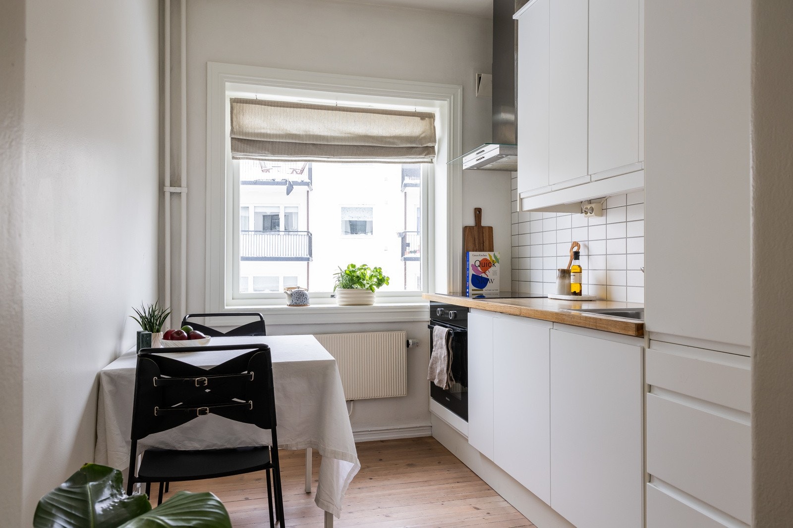 Pent og moderne, separat kjøkken som består av hvite, glatte fronter og benkeplate i heltre. Galleribilde