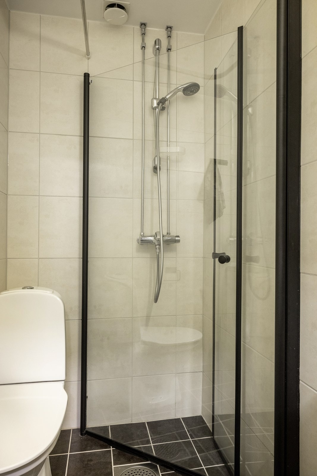 Badet inneholder toalett, servant, dusjhjørne med svingbare glassdører og opplegg for vaskemaskin. Galleribilde