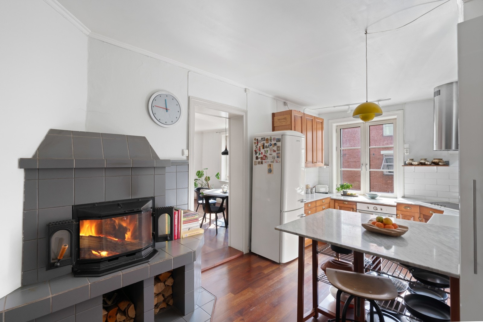 Veggene over benken er kledd med hvite, blanke fliser som står godt til resten av interiøret, og i et hjørne på kjøkkenet er det en sjarmerende peis med innsats. Galleribilde