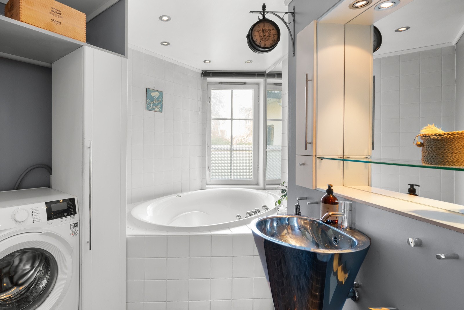 Her er det et innfliset badekar ved vinduet, opplegg for vaskemaskin i nisje og dusj i hjørnet bak en vegg av glassbyggerstein. Galleribilde