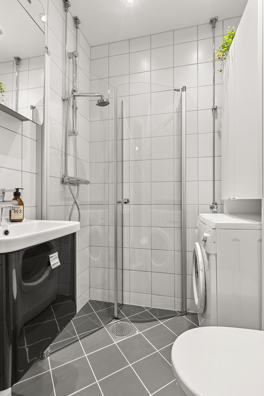 Videre har badet dusjhjørne med svingbare glassdører og vegghengt klosett. Det er opplegg for vaskemaskin. Galleribilde