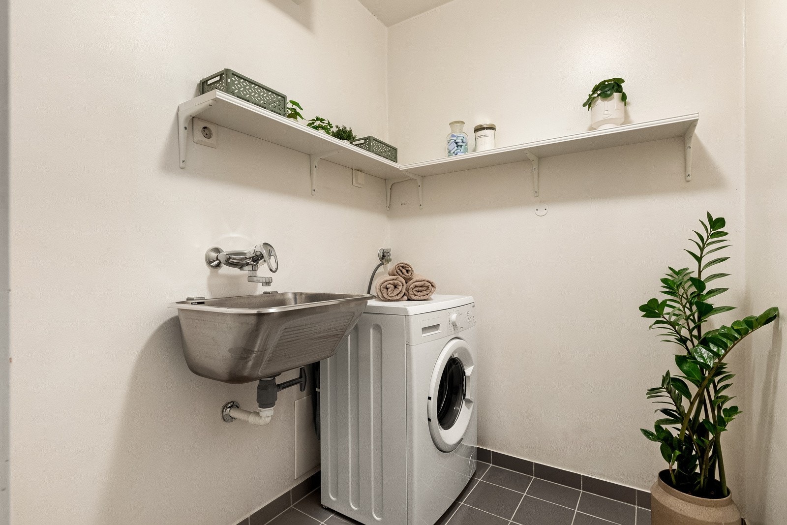 Svært praktisk vaskerom som inneholder utslagsvask rustfritt stål og opplegg for vaskemaskin. Videre er det plass til oppbevaring. Galleribilde