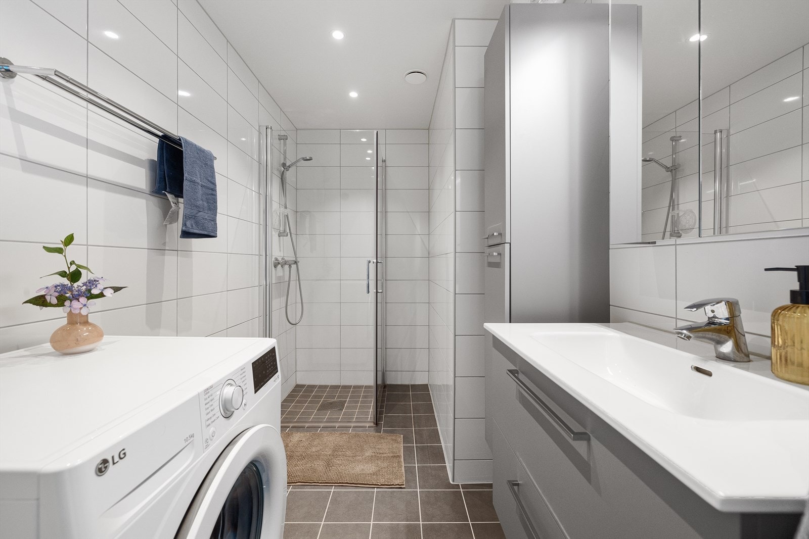 Servantinnredningen glatte fronter og heldekkende servant med speilskap og belysning over. Dusjhjørne med innfellbare glassdører og opplegg for vaskemaskin. Galleribilde