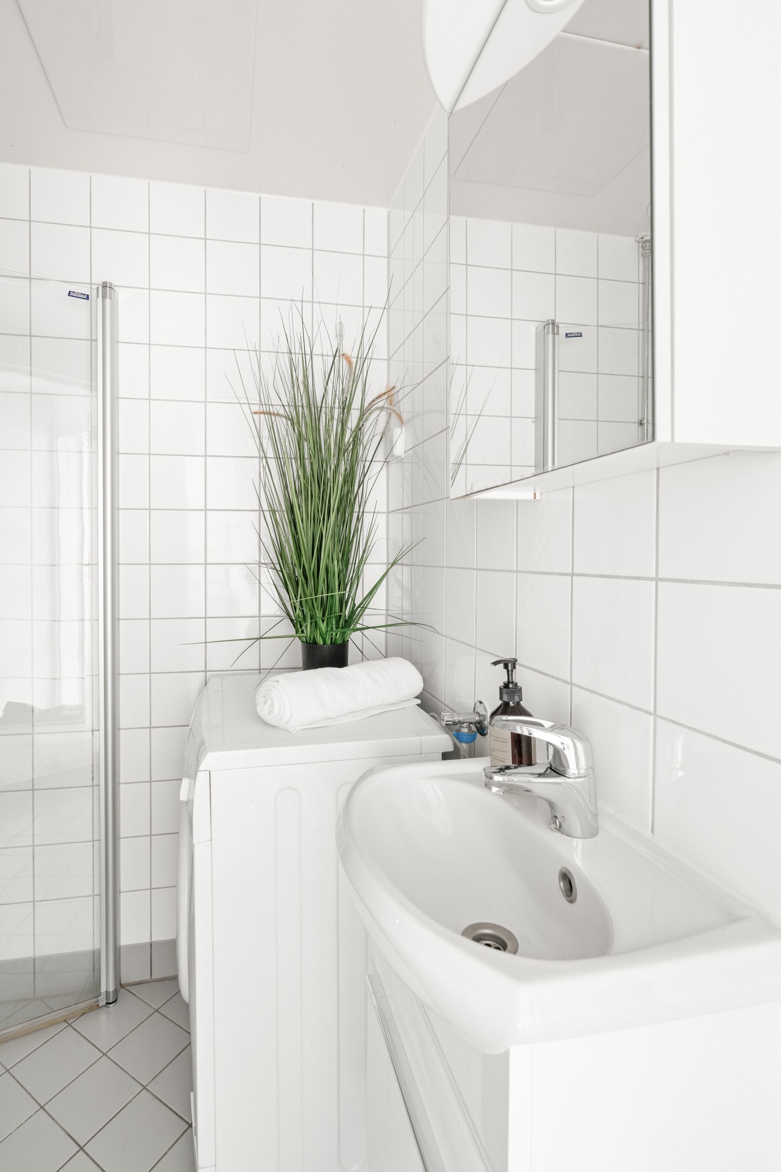 Det er baderomsinnredning med servant, speil på vegg, toalett og dusjhjørne. Det er opplegg for vaskemaskin Galleribilde