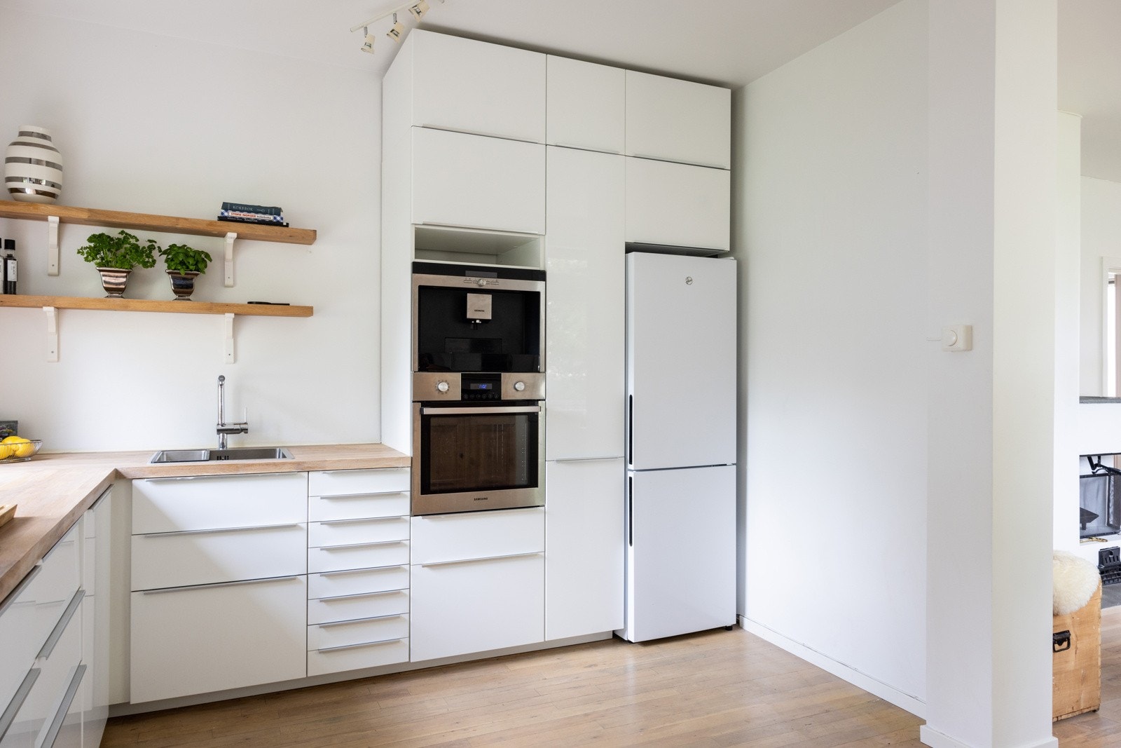 Tidsriktig og velholdt Ikea kjøkkeninnredning fra 2014 med hvite høyglansfronter og heltre benkeplate. Galleribilde