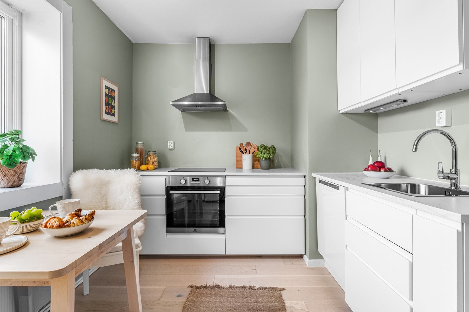 Veggflatene er malt i en moderne tone, og selve innredningen fra 2021 har hvite, glatte fronter, dempefunksjoner og oppvaskkum av stål nedfelt i en laminert benkeplate. Galleribilde