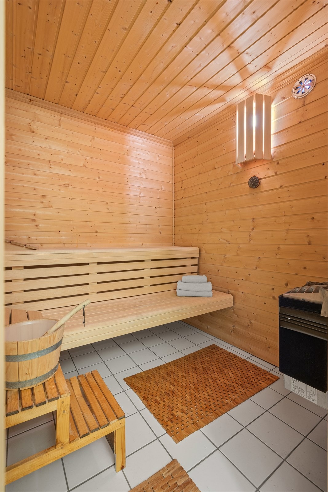 Fra bad/vaskerom er det også inngang til egen badstue. Badstuen har flislagt gulv ogpanel på vegger og i innvendig tak. Den er innredet med plassbygde benker av tre og elektrisk badstuovn. Ventilert med naturlig utlufting. Galleribilde