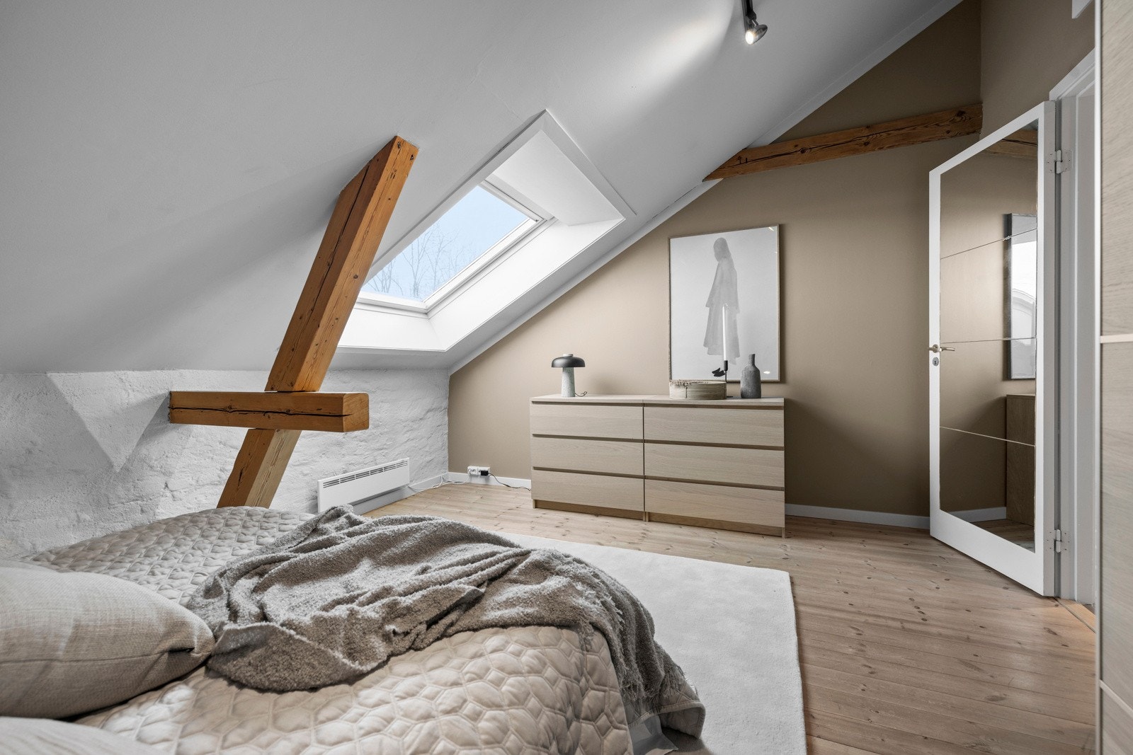 Den generøse takhøyden og det store takvinduet slipper inn mye naturlig lys, noe som gjør soverommet lyst og innbydende. Galleribilde