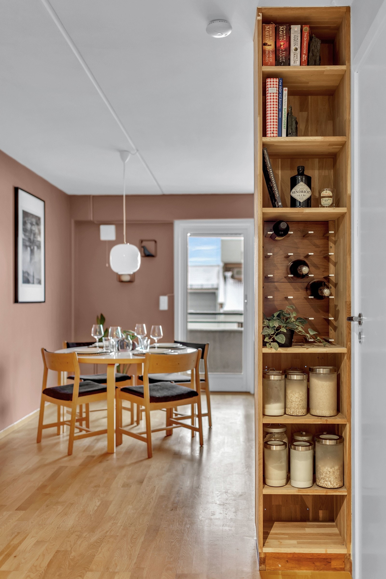 Plassbygget hylle mellom kjøkken og stue, med egen hylleseksjon for vin. Galleribilde