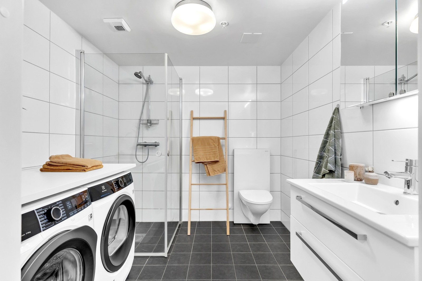 Pent og romslig bad fra 2018 med fliser på gulv og vegger samt malt himling. Vannbåren gulvvarme. Heldekkende servant med servantskuffer og speil på vegg med integrert belysning. Dusjhjørne med pen dusjgarnityr på vegg og stilrene, innfellbare dusjvegger Galleribilde