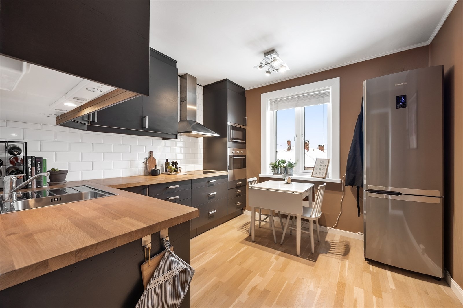 Funksjonelt kjøkken med spiseplass og integrerte hvitevarer. Galleribilde