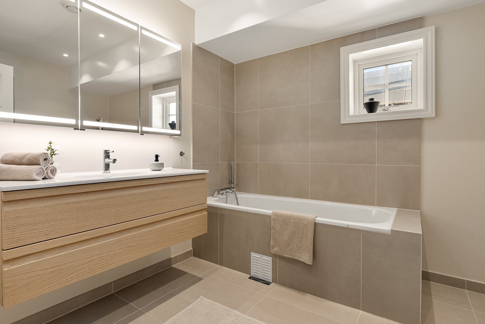 I 2. etasje finner man to innholdsrike bad, begge utstyrt med moderne fasiliteter og stilige overflater. badet har flislagt gulv med varme, og en kombinasjon av malte og flislagte overflater som gir et elegant preg. Galleribilde