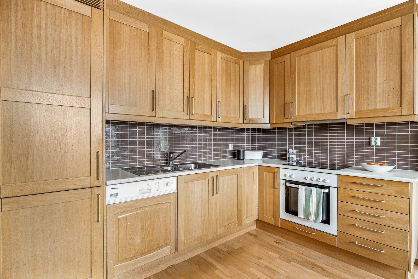 Kjøkkenet har takhøy innredning med god lagringsplass i skap, utstyrt med integrerte hvitevarer som medfølger. Galleribilde