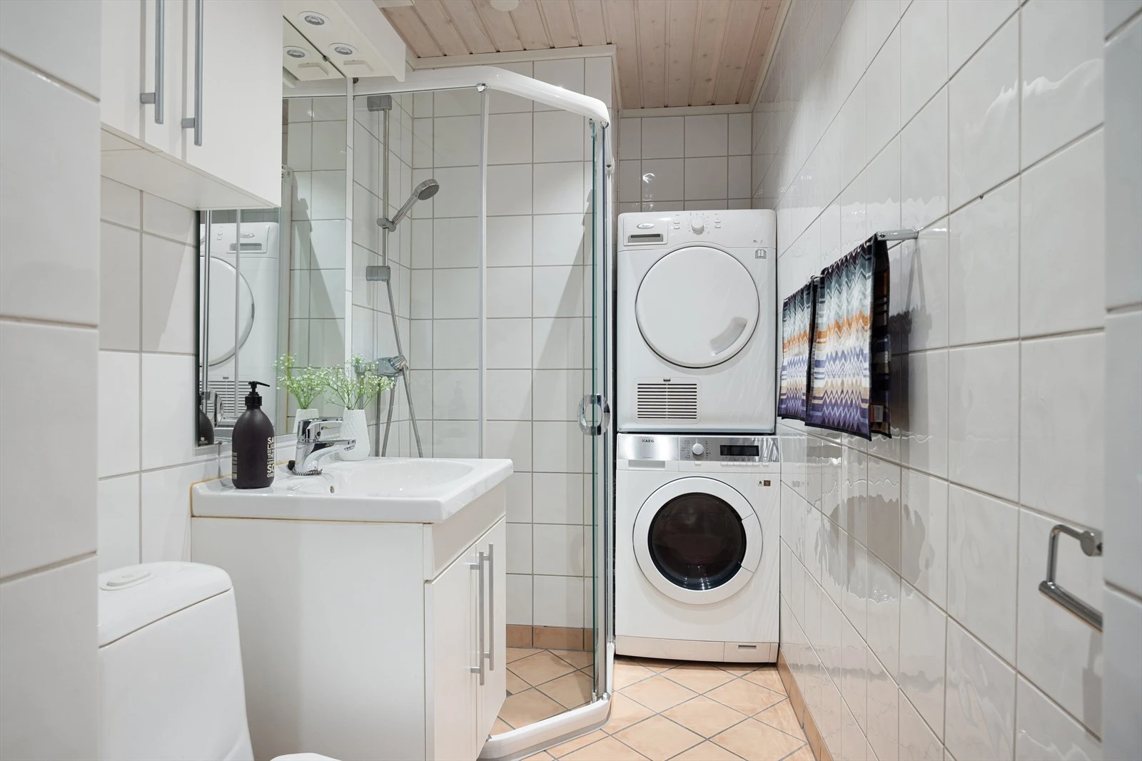 Pent flislagt baderom med gulvvarme og opplegg for både vaskemaskin og tørketrommel. Badet har et praktisk dusjhjørne med skyvedører. Galleribilde