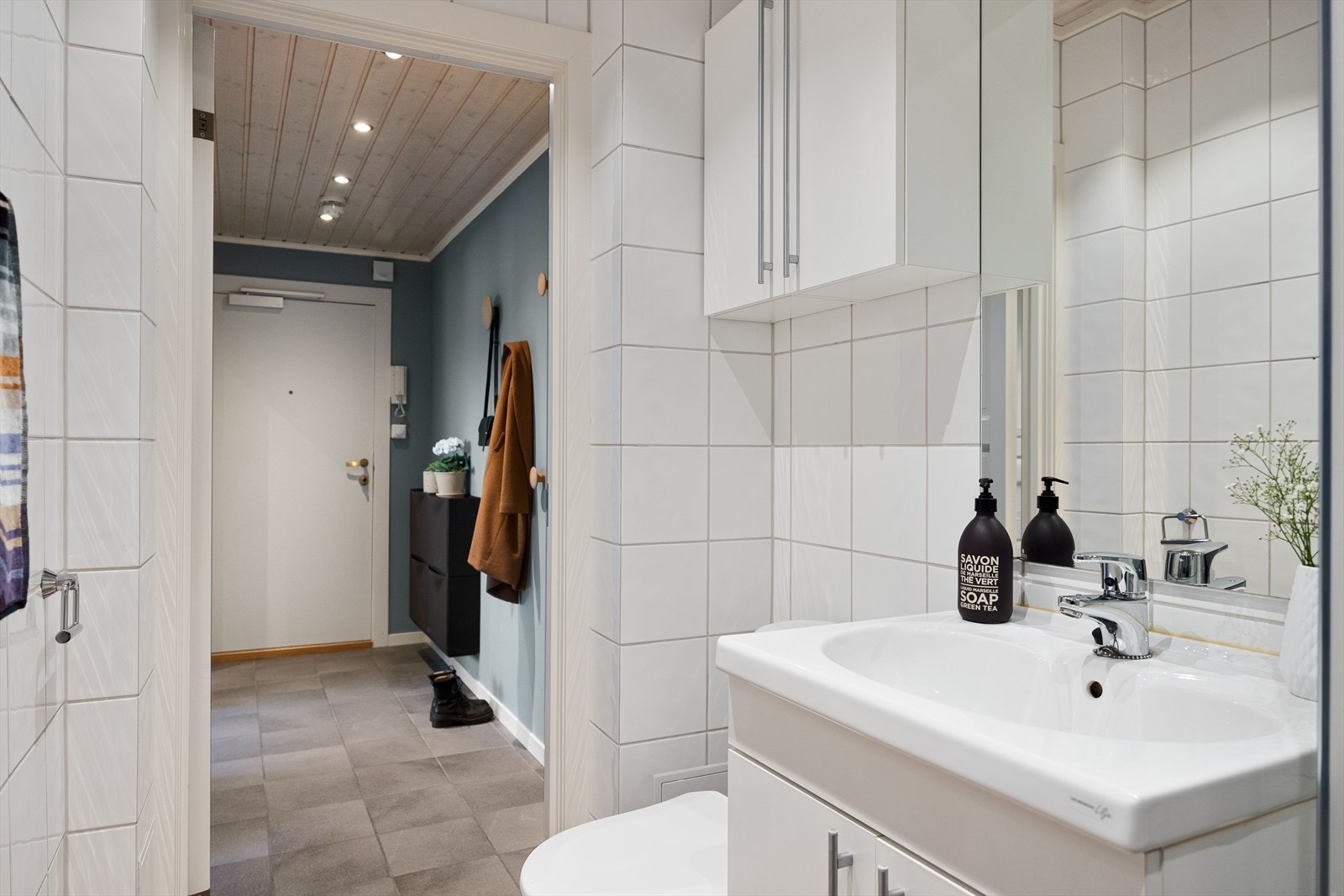 Baderommet er utstyrt med servantskap med glatte, folierte fronter og heldekkende servant, speil og lysarmatur over servant, samt et gulvmontert klosett. Galleribilde