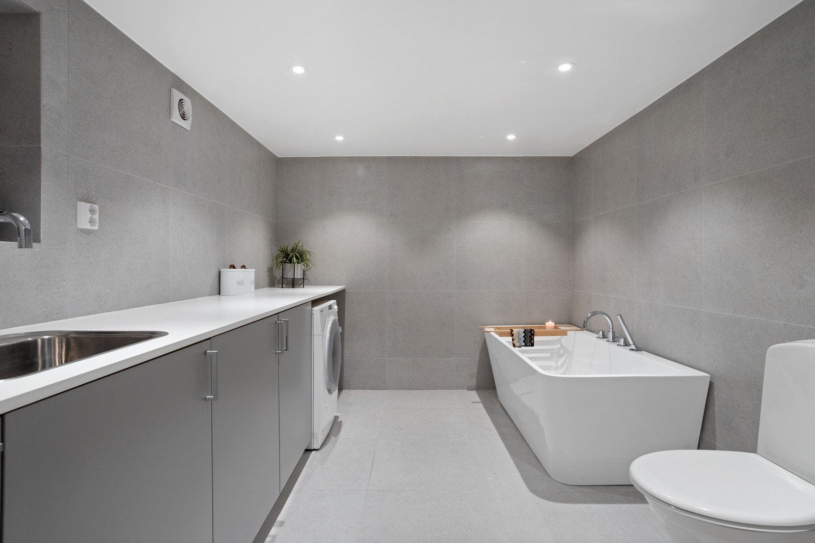 Vaskerom med opplegg for vaskemaskin og tørketrommel med badekar og toalett. Galleribilde