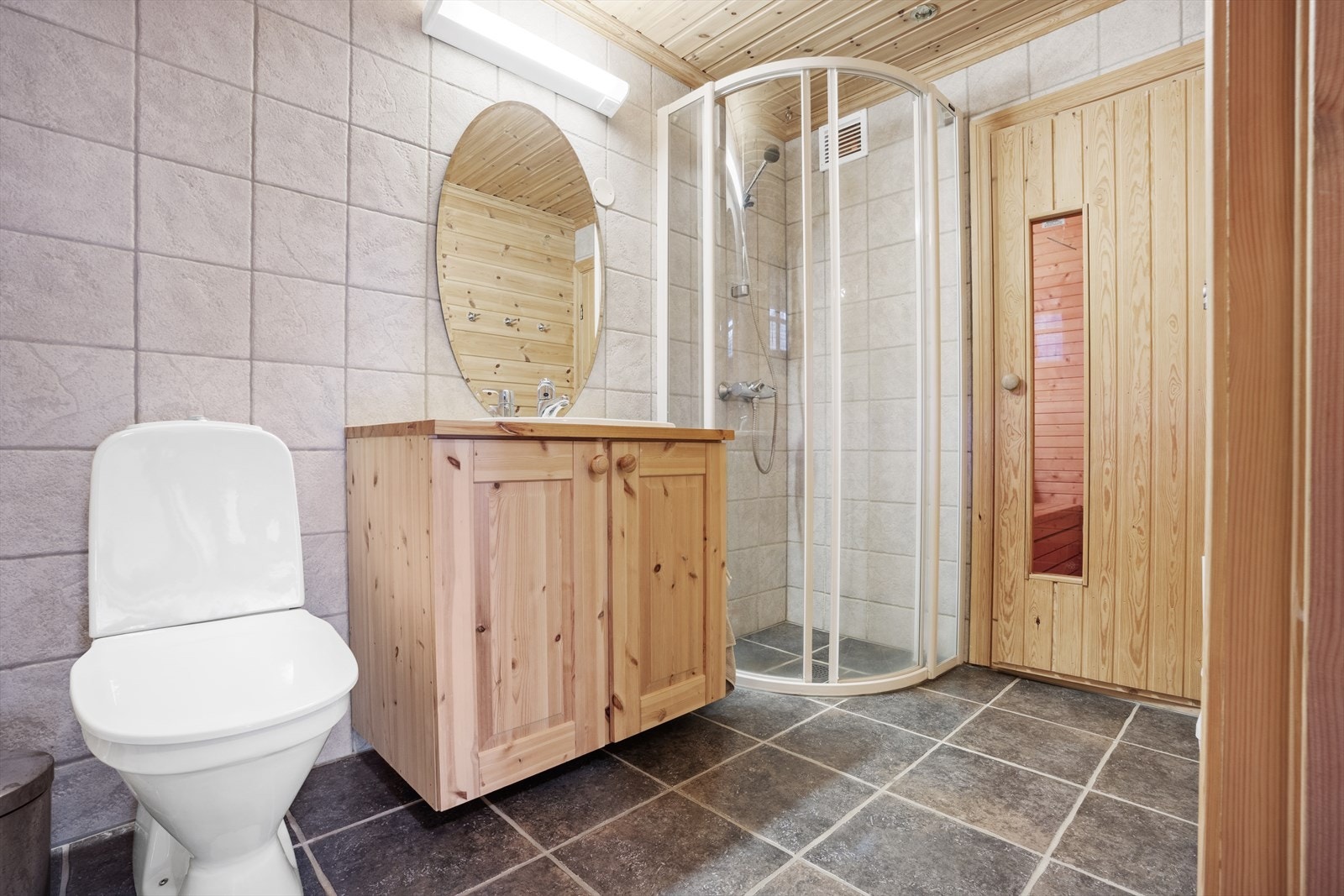 Badet er innredet med fliser på gulvet og vegger, som gir en tidløs og praktisk stil. Opplegg for vaskemasin på badet Galleribilde