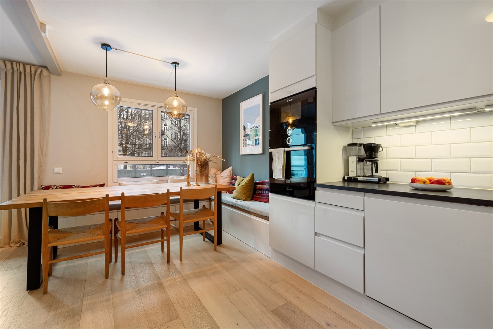 Stilrent og flott kjøkken fra HTH med hvite, slette fronter, fliser mellom benk- og overskap og benkeplate i laminat. Galleribilde