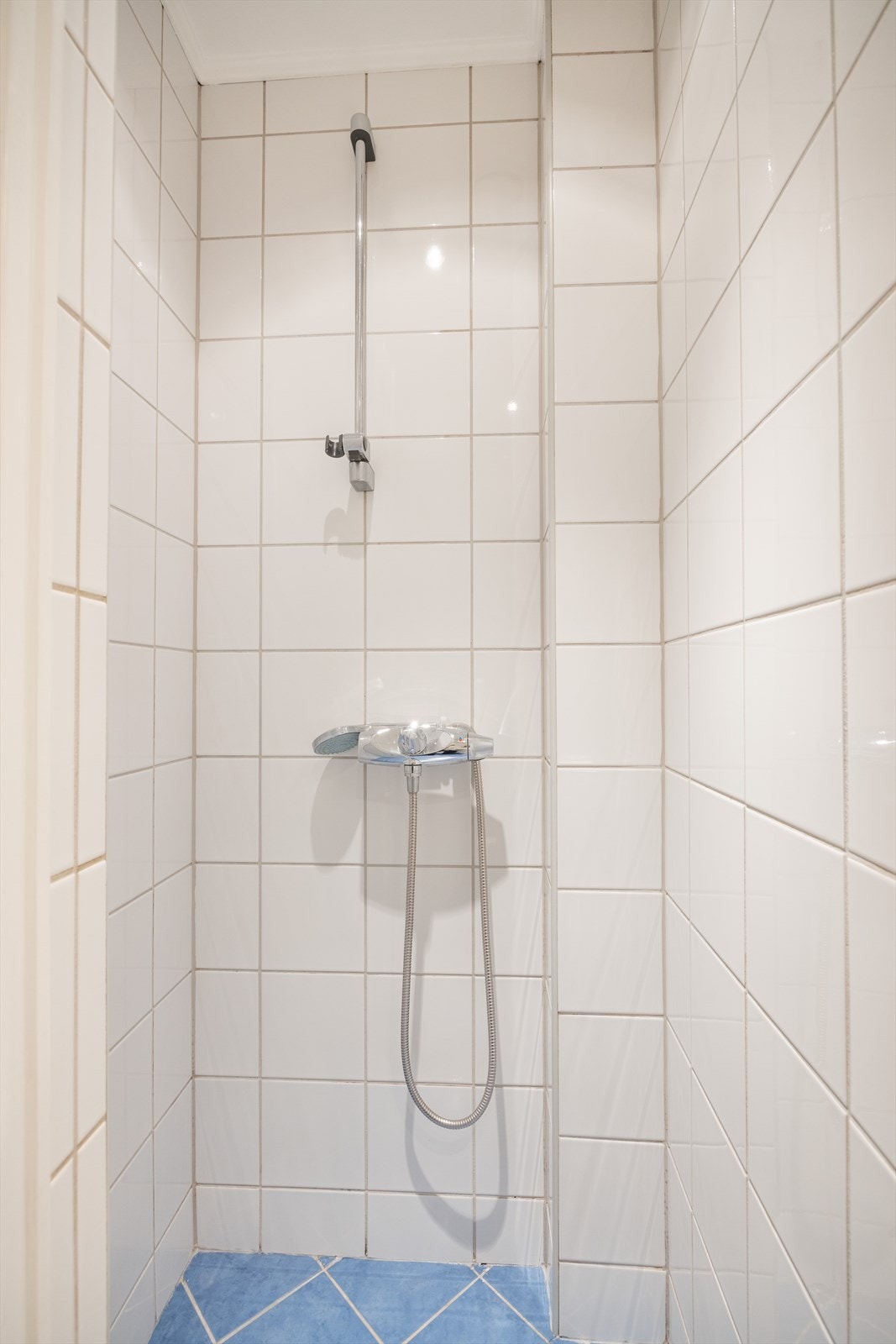 Badet er innredet med vegghengt toalett, servant med innredning og dusjhjørne. Galleribilde