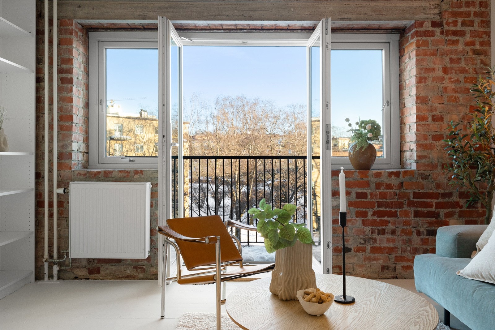Stuen har en stilig kontrastvegg med blottlagt teglstein samt store vindusflater som sørger for godt med naturlig lys og grønt utsyn på sommerstid. Galleribilde