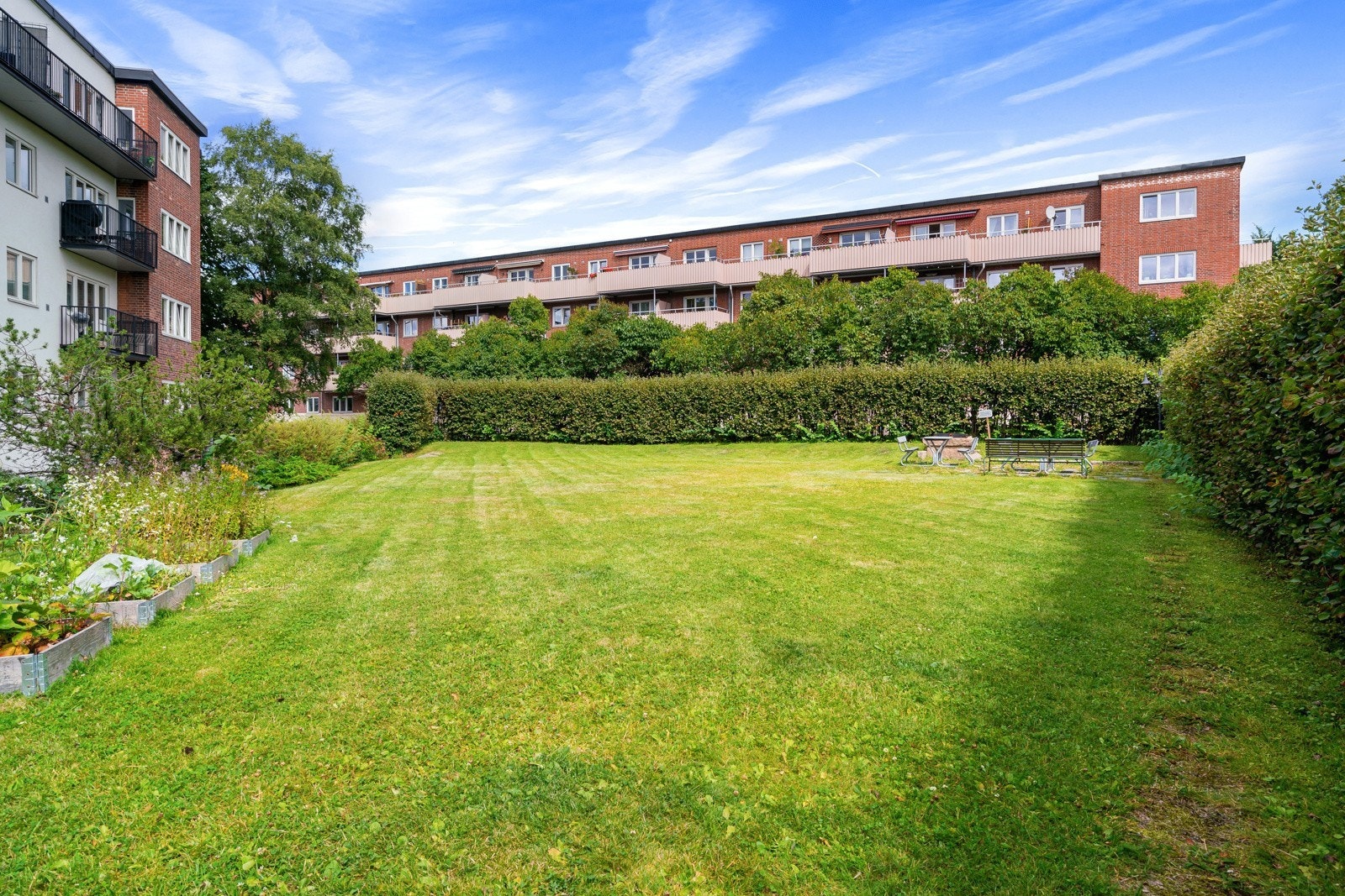 Borettslagets idylliske og parkmessige opparbeidede hageanlegg med parsellbokser, gressplen, variert beplantning og sittepenker. Galleribilde