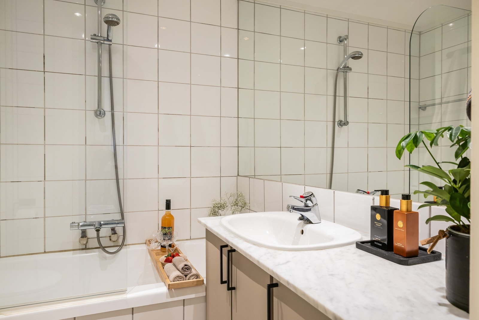 Tidløst og pent flislagt bad med badekar, dusj, servant og toalett. Galleribilde