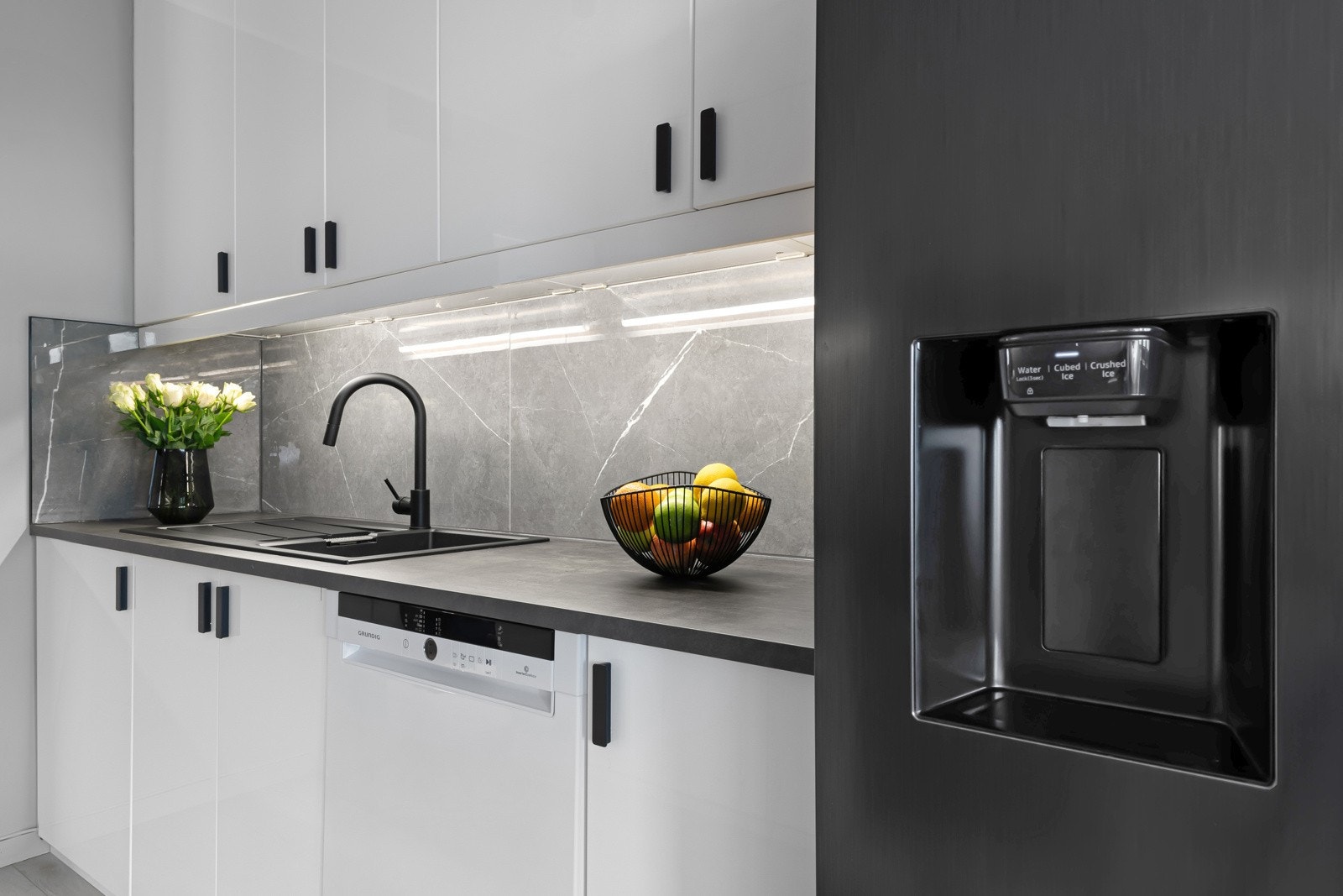 Kjøkkeninnredningen var ny i 2021/2022 og er montert langs to parallelle vegger. Frontene er i hvit høyglans med sorte håndtak og benkeplatene er i grå laminat med betonglook. Galleribilde