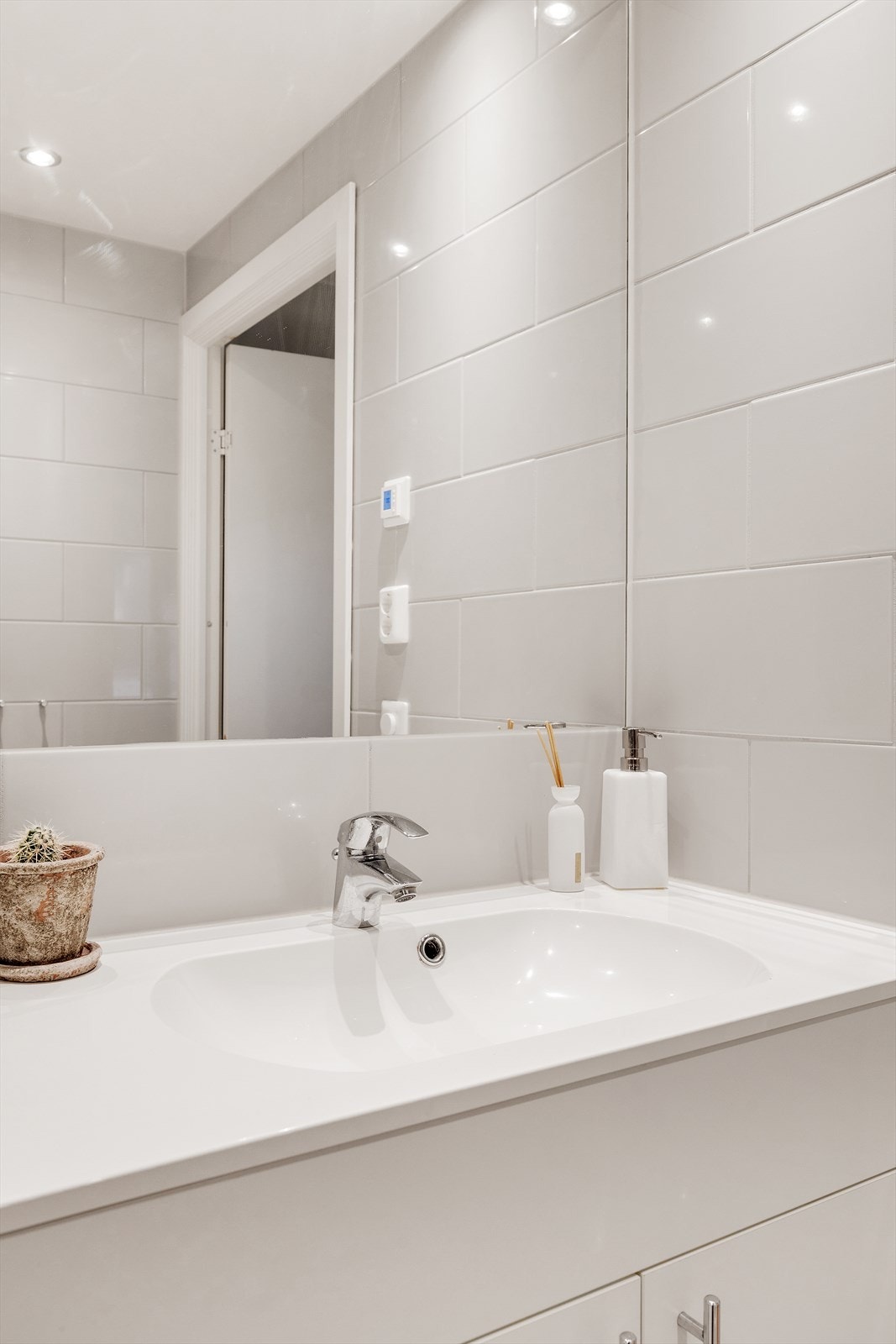 Veggmontert innredning med heldekkende servant og ett-greps armatur. Speil over servant og stikkontakt på vegg. Galleribilde