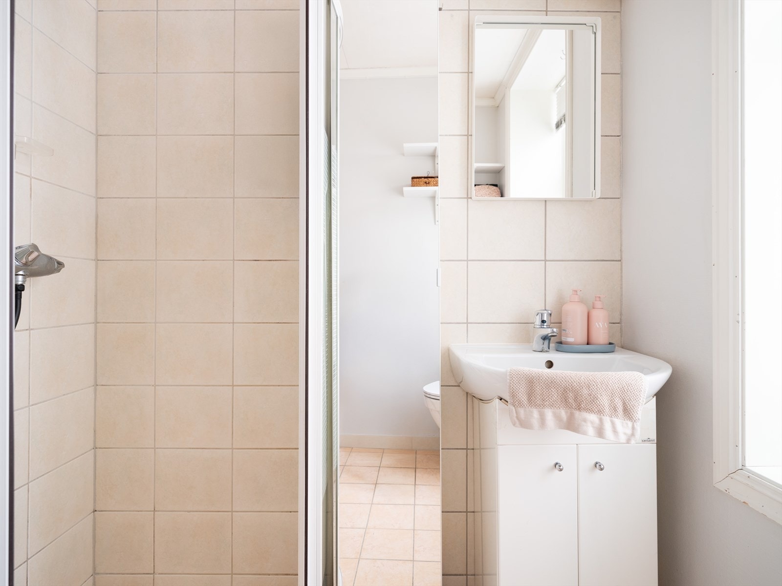 Badet består av dusjvegger av glass, gulvmontert toalett og innredning med servant. Galleribilde